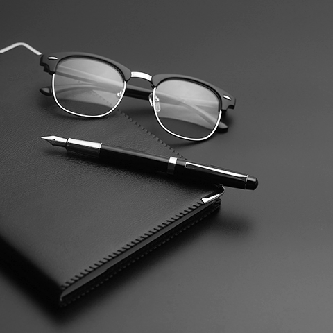 fountain pen and glasses resting on a leather notebook