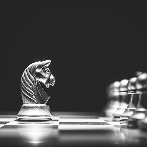 closeup on chess board with knight facing a row of pawns