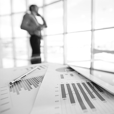 Business Professional looks out window with financial papers on a table